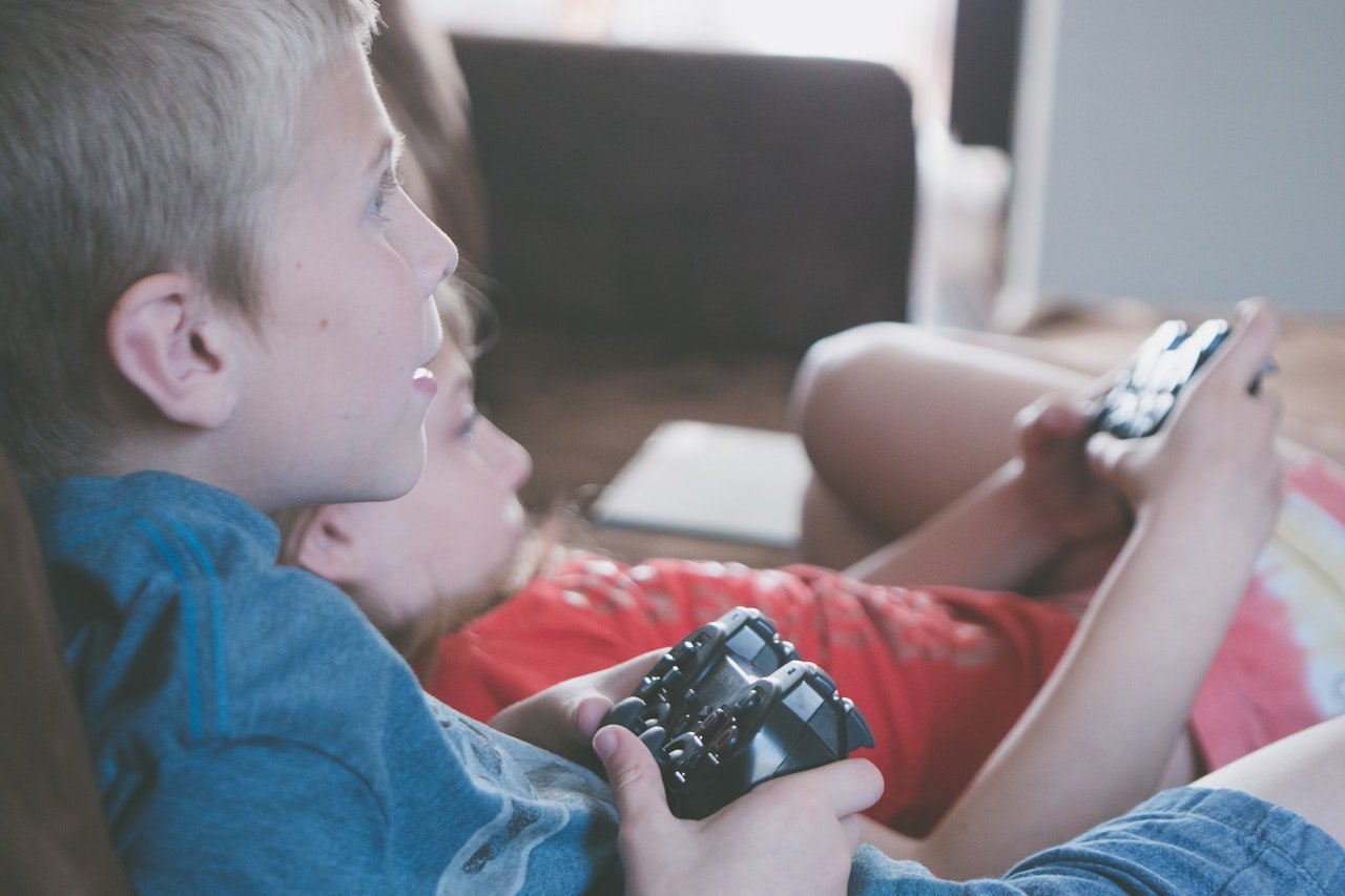 Deux enfants qui jouent aux jeux vidéo sur un canapé