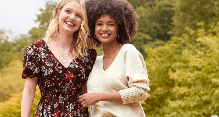 Joe Browns offers page image featuring two nicely dressed women laughing in a field with trees in the background