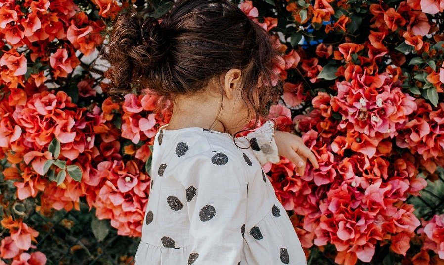 Mädchen mit weißer Bluse und roten Blumen im Hintergrund