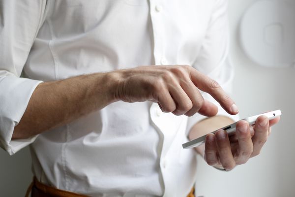 Homme en chemise blanche tenant un smartphone