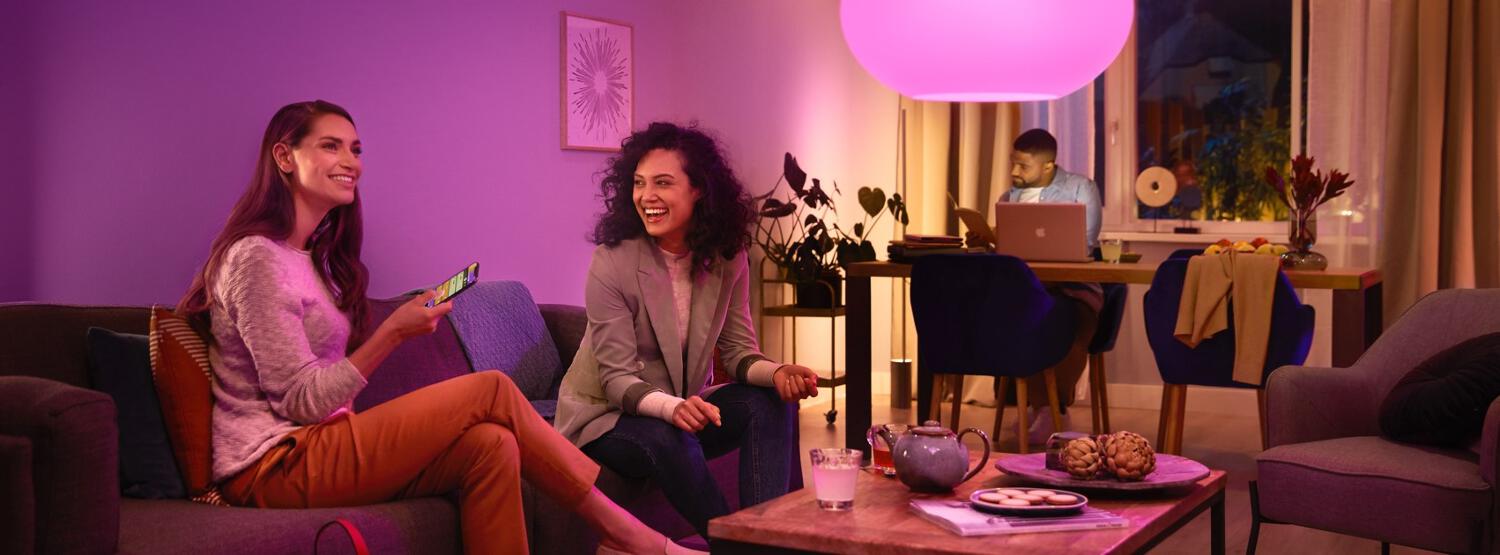 Femme allumant une lampe connectée Philips Hue avec son smartphone
