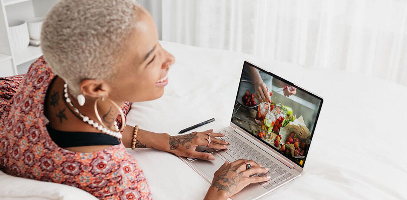 Lenovo ways to save banner. Image features a woman using a laptop on a bed