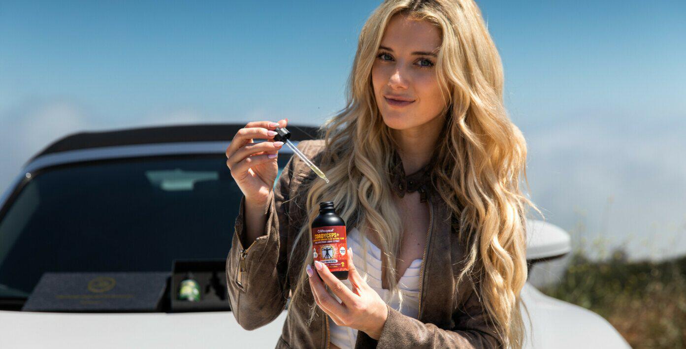 Life Cykel deals page image featuring an attractive woman holding Life Cykel drops in front of a car