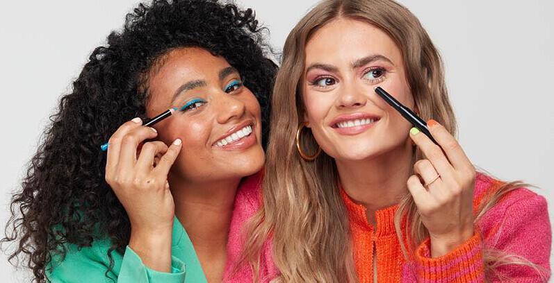LOOKFANTASTIC new season deals image showing 2 women in bright clothes applying cosmetics