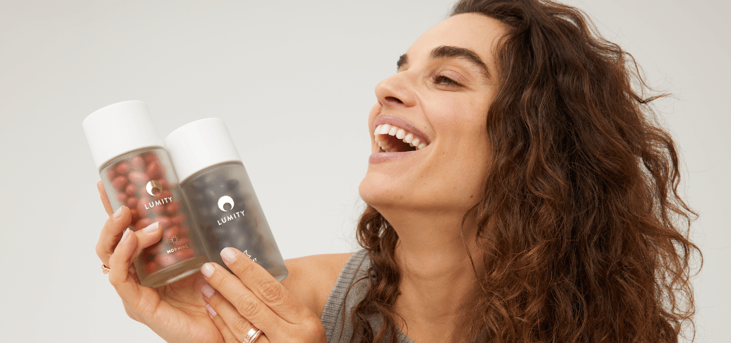 Lumity savings guide image - Woman smiling while holding up Lumity branded supplements