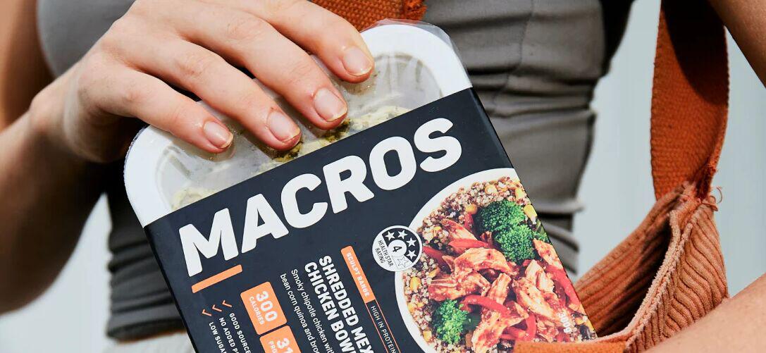 Macros deals page banner showing a close up of a person putting a branded ready-meal in their bag