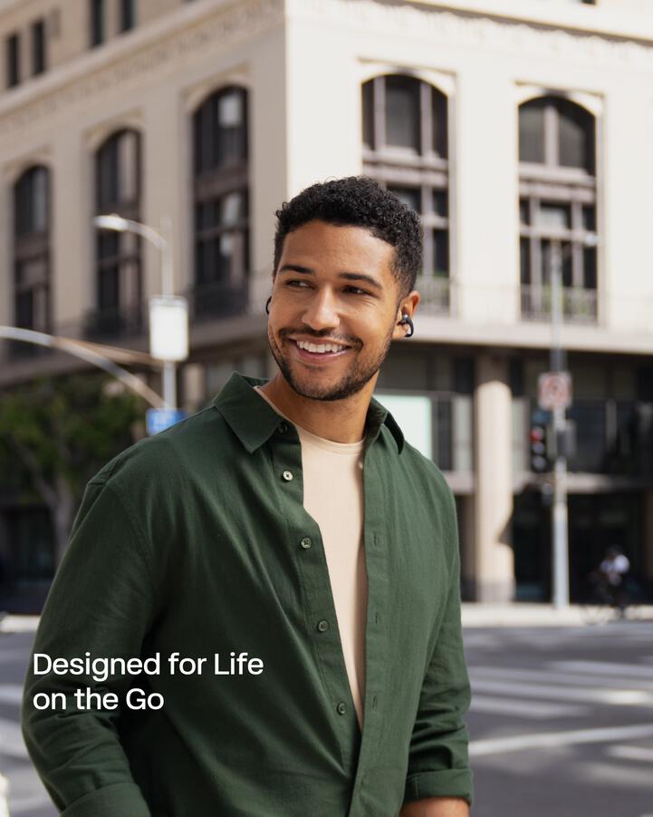 Man using Shokz headphones while walking in a city