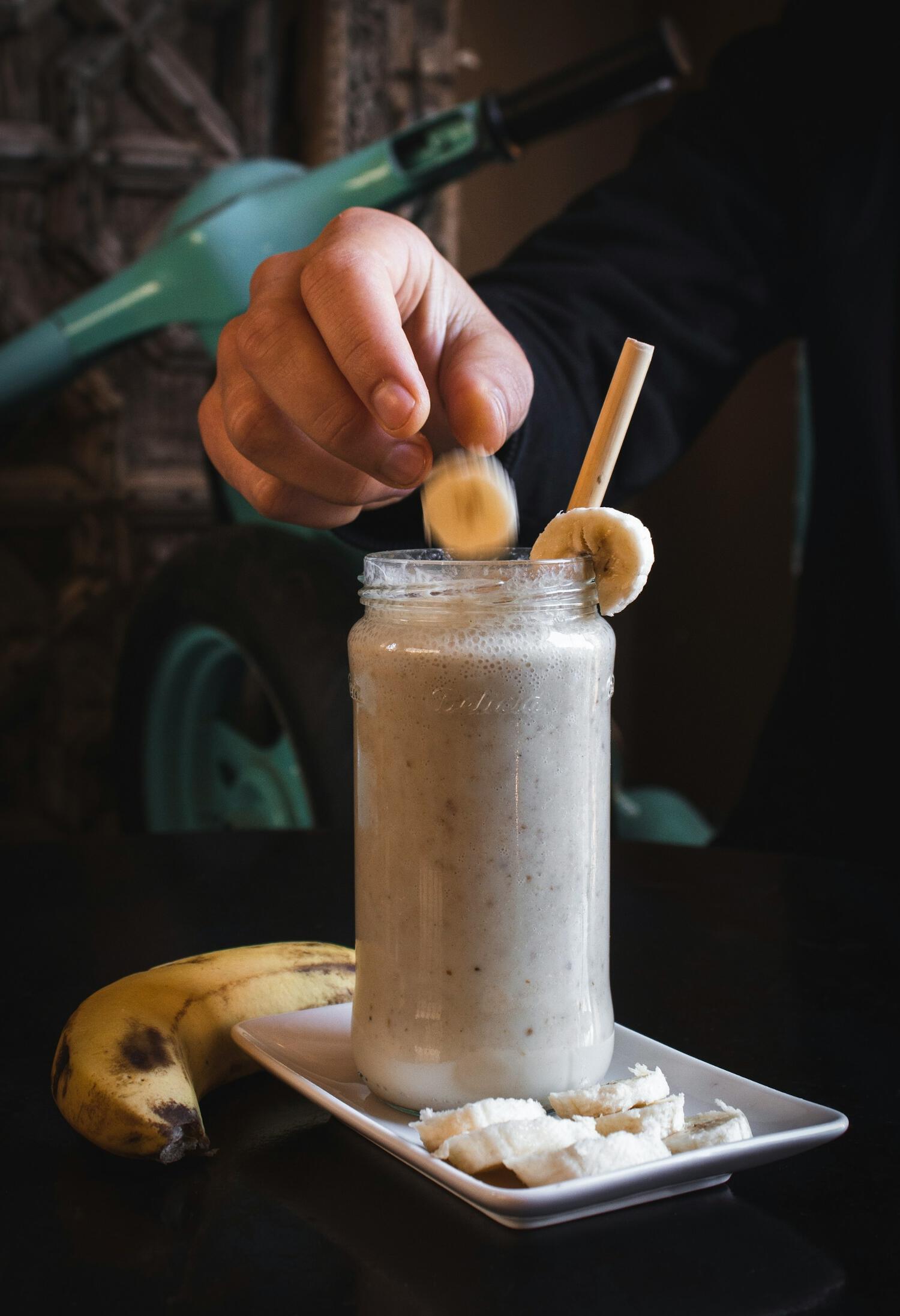 Personne ajoutant une rondelle de banane dans un milkshake protéiné
