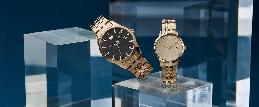 Deux montres en or Watch Station pour homme et femme sur des cubes en plexiglass