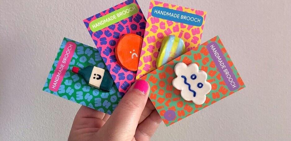 MOO deals page image showing a hand holding personalised brooches on card backs