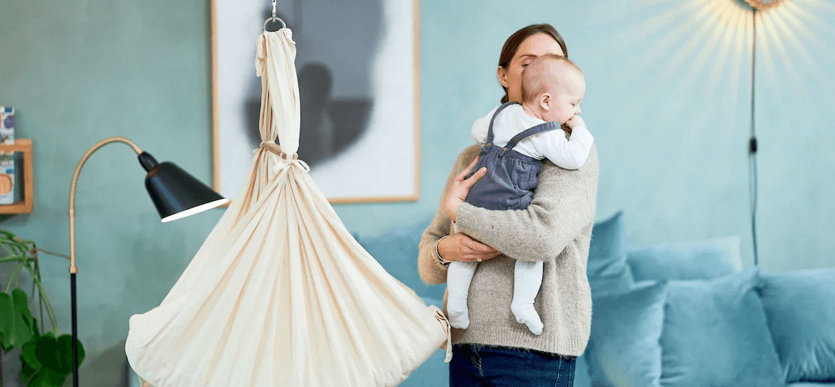 Mutter und Kind stehen im Wohnzimmer vor einer Moonboon-Federwiege