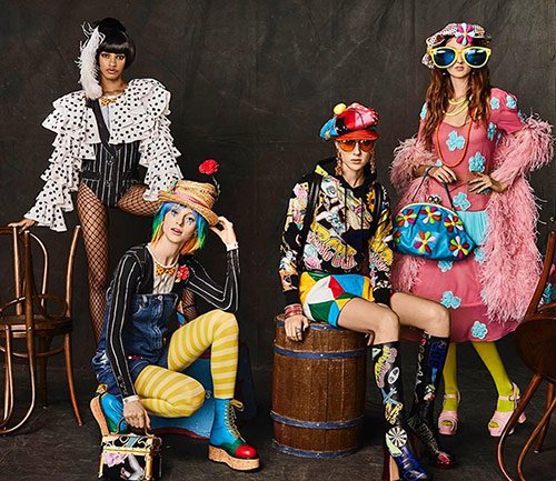 Quatre mannequins Moschino sur fond gris avec vêtements colorés