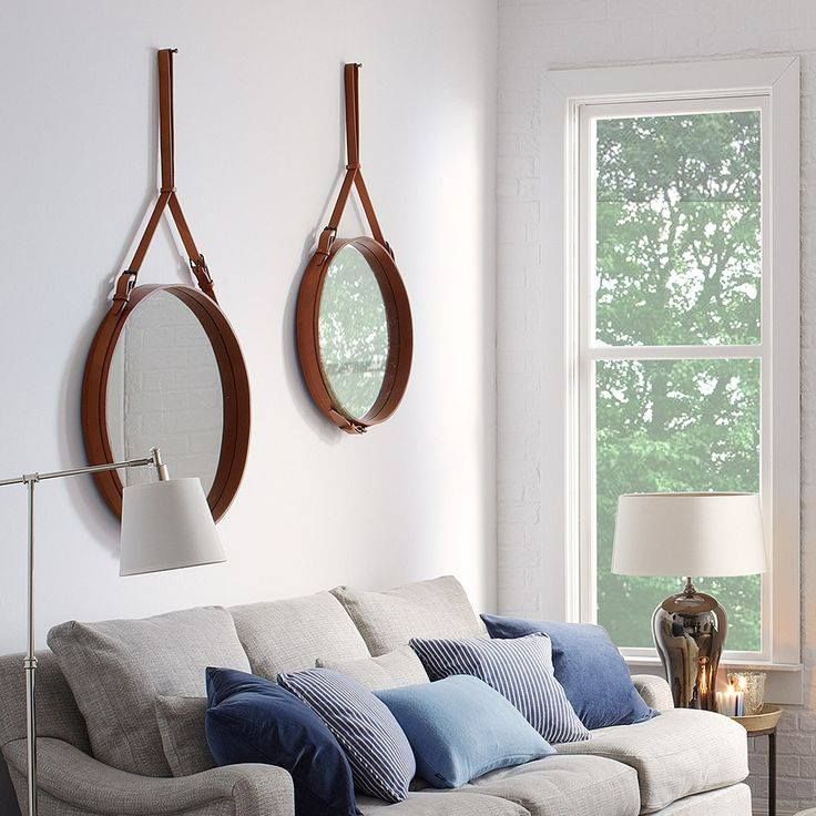 Canapé gris avec coussins bleus et mirroires ronds accrochés au mur