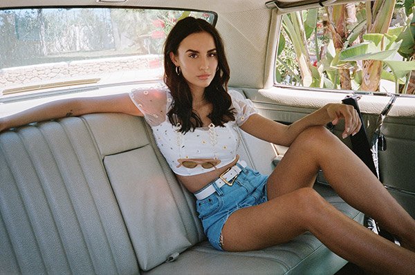 Mannequin assise à l&apos;arrirèe d&apos;une voiture avec short en jean et crop top blanc Nasty Gal