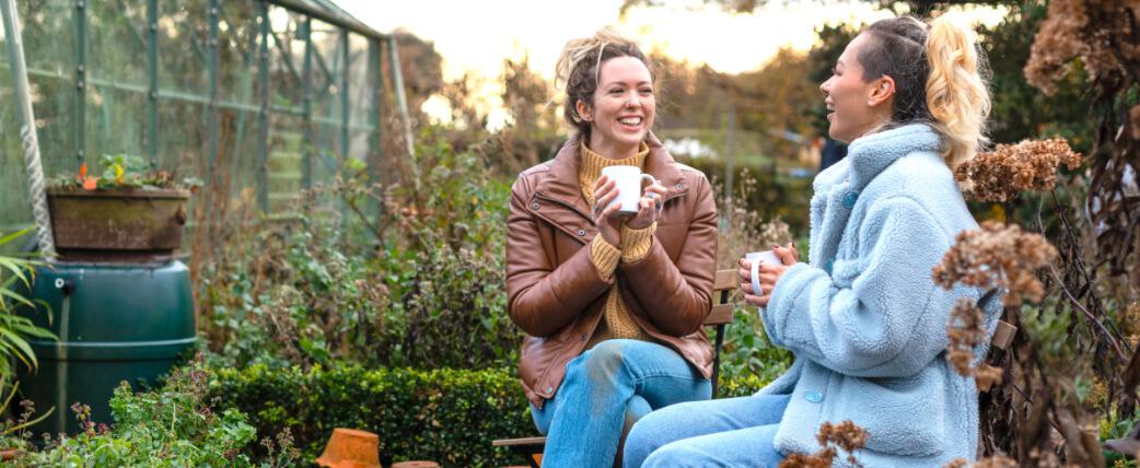 two women enjoying a social cup of tea in garden