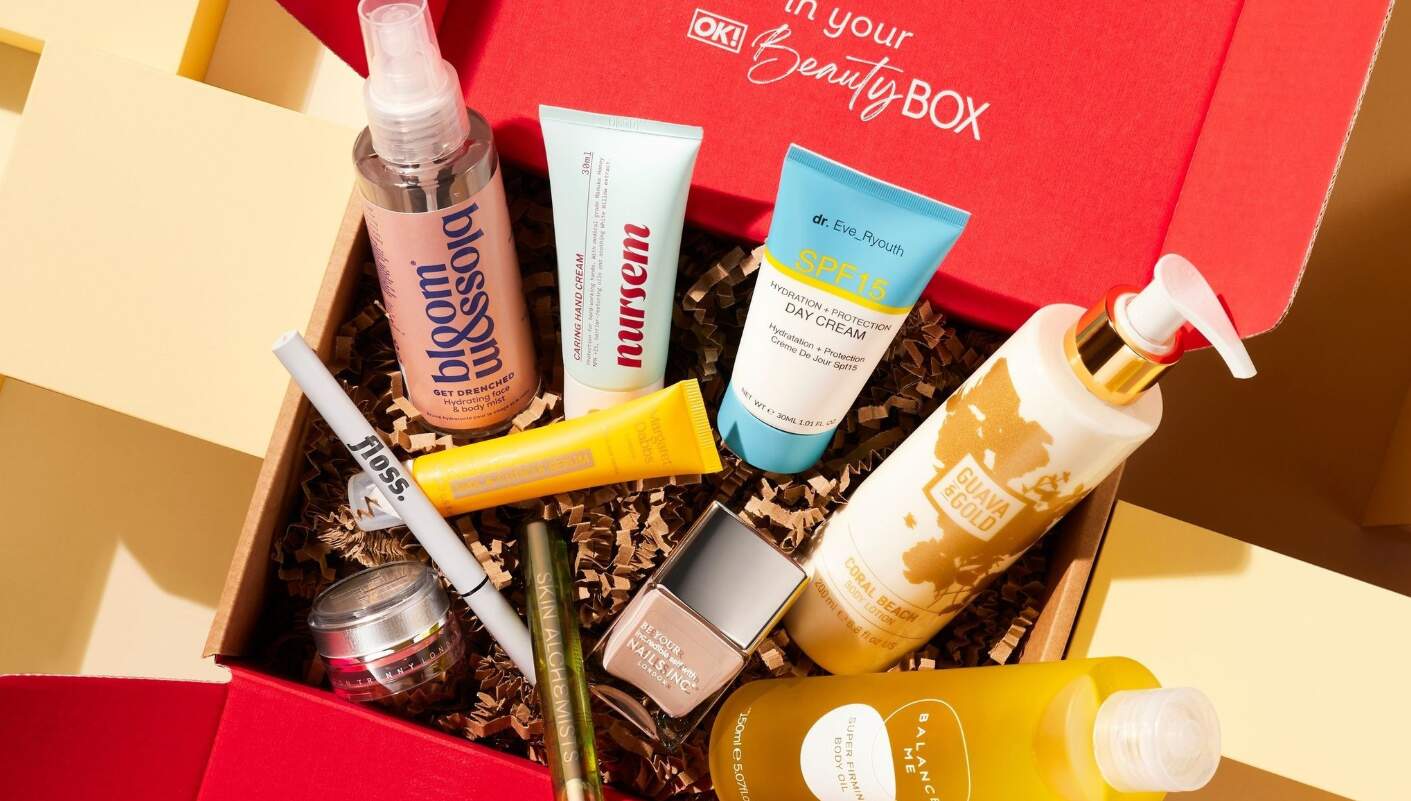 OK Beauty Box how to save banner - Ten beauty products sitting in a red branded cardboard box. Products include a day cream, body lotion and nail polish