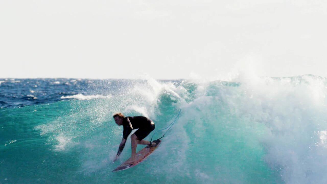 Man surfing on a big wave in surf gear from Quiksilver