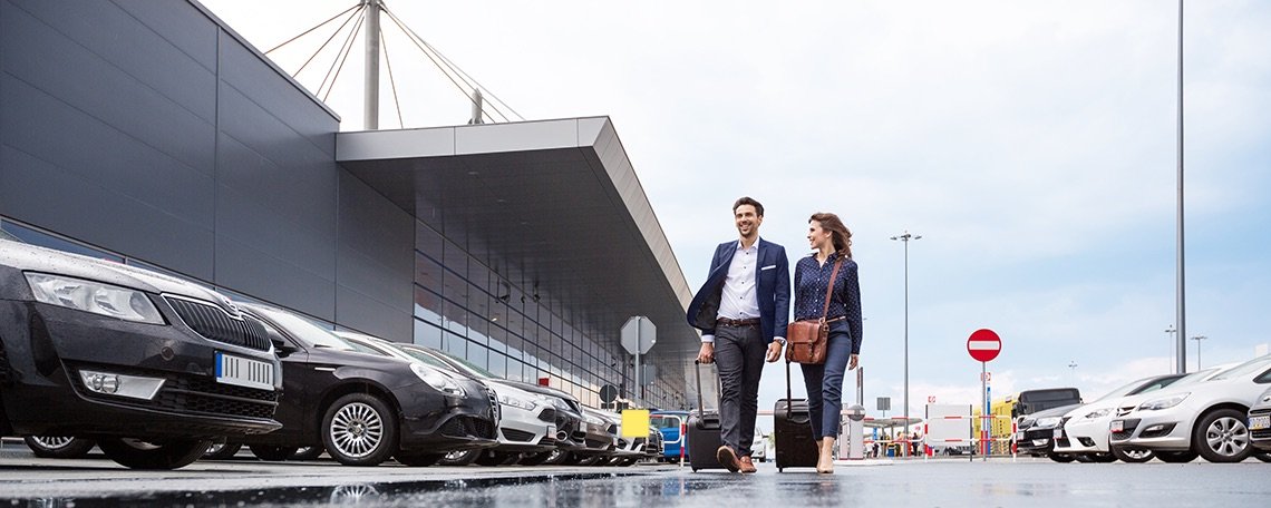 Park and Go Airport Parking banner - couple in airport car park with suitcases