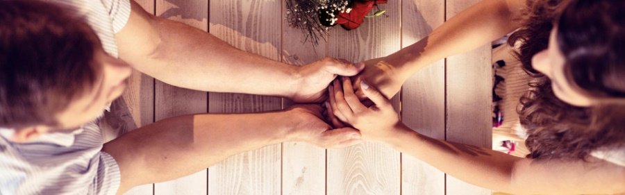 Banner der Seite für Parship Gutscheine: Mann und Frau sitzen sich am Tisch gegenüber und halten Händchen