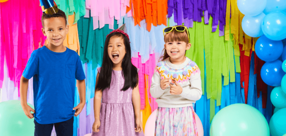 Party Delights savings page image - Three smiling kids wearing party accessories in front of a multicoloured background