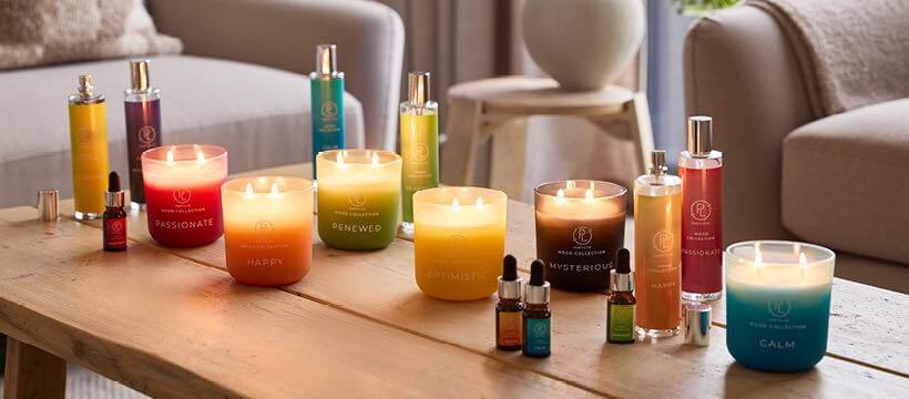 PartyLite savings guide banner featuring a selection of colourful fragrances and candles on a coffee table in room setting