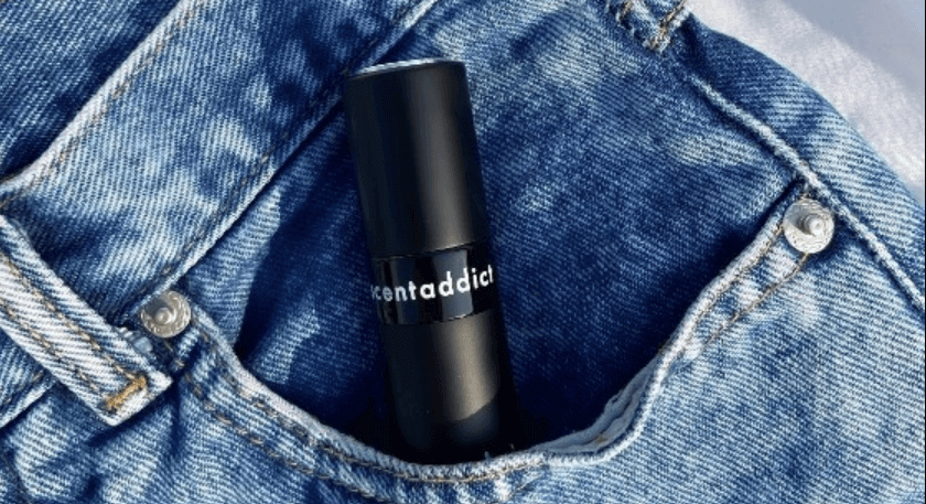 A small black perfume sample in the pocket of denim jeans. Text on the bottle reads: Scent Addict