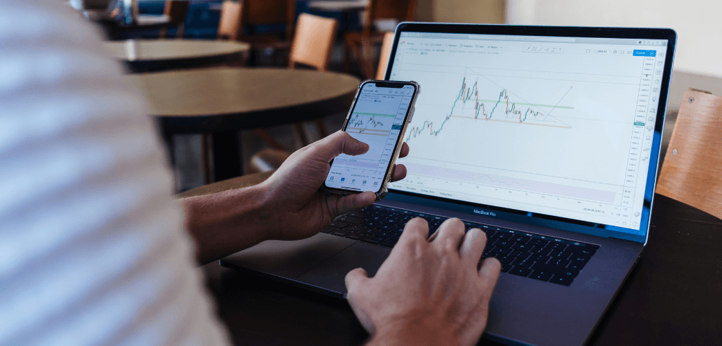 picture of a person checking finance stats on a smartphone and laptop