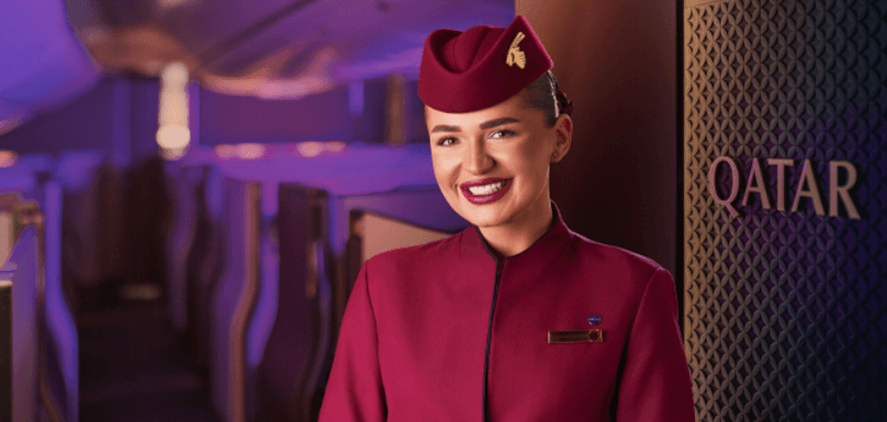 Qatar Airways ways to save image - A smiling female member of cabin crew wearing the company uniform in plane interior