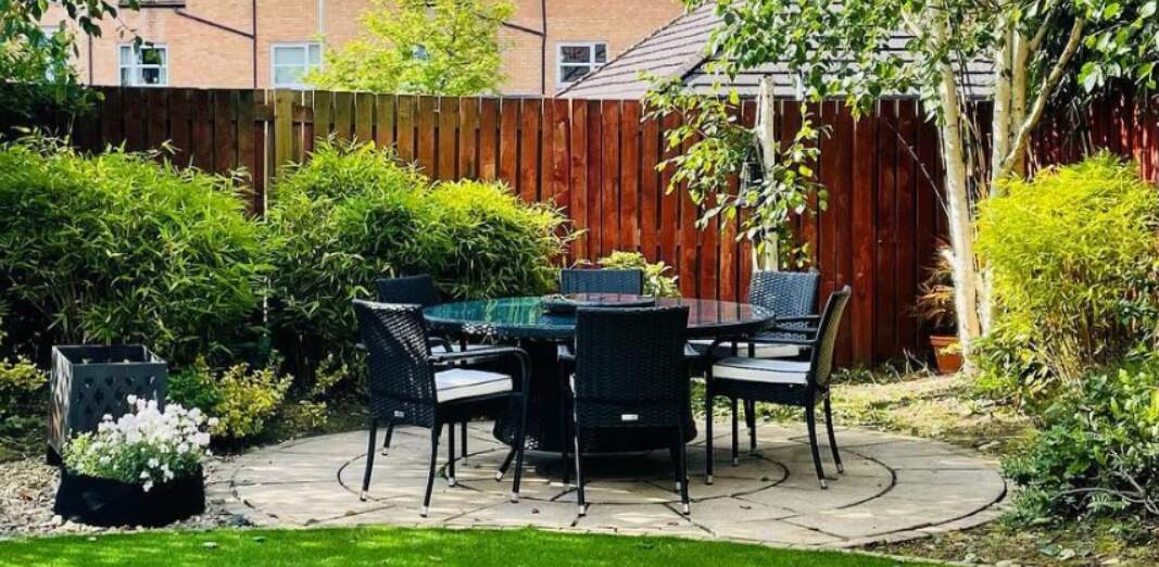 Rattan Direct ways to save image - A black garden dining set in a large lanscaped garden