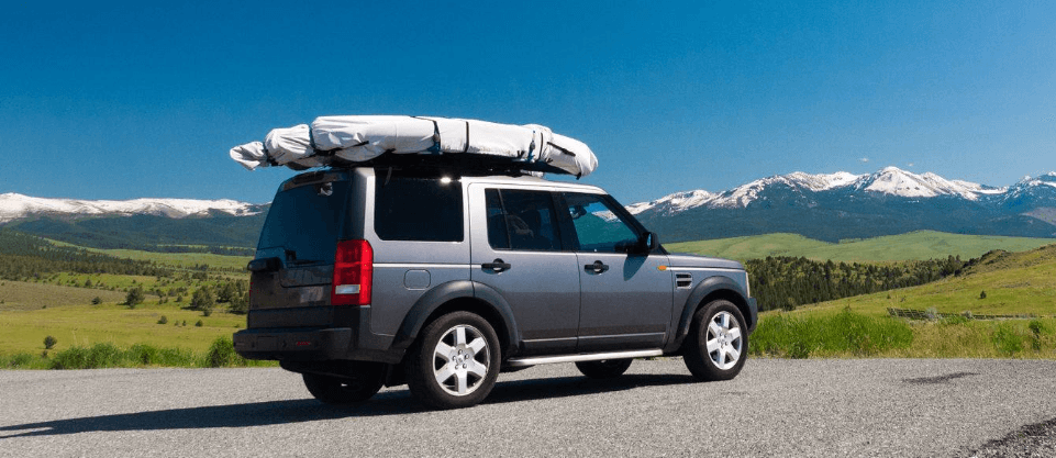Reduce My Excess more ways to save banner. Image shows a vehicle that has a roof rack full of items in front of a scenic background