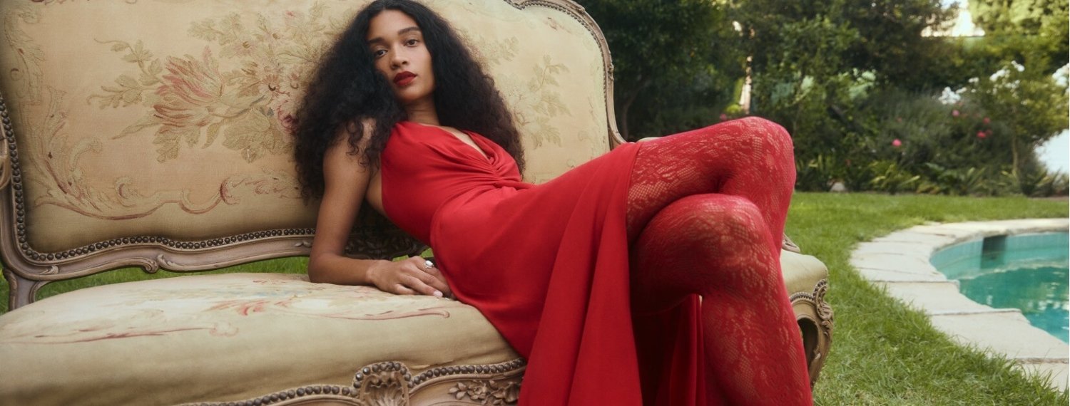 Woman lounging on a chair in a red dress and lace tights from Reformation
