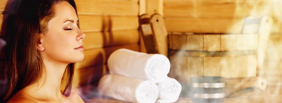 Banner der Sauna24 Gutscheinseite: eine Frau genießt die Ruhe in der Sauna mit Saunazubehör im Hintergrund