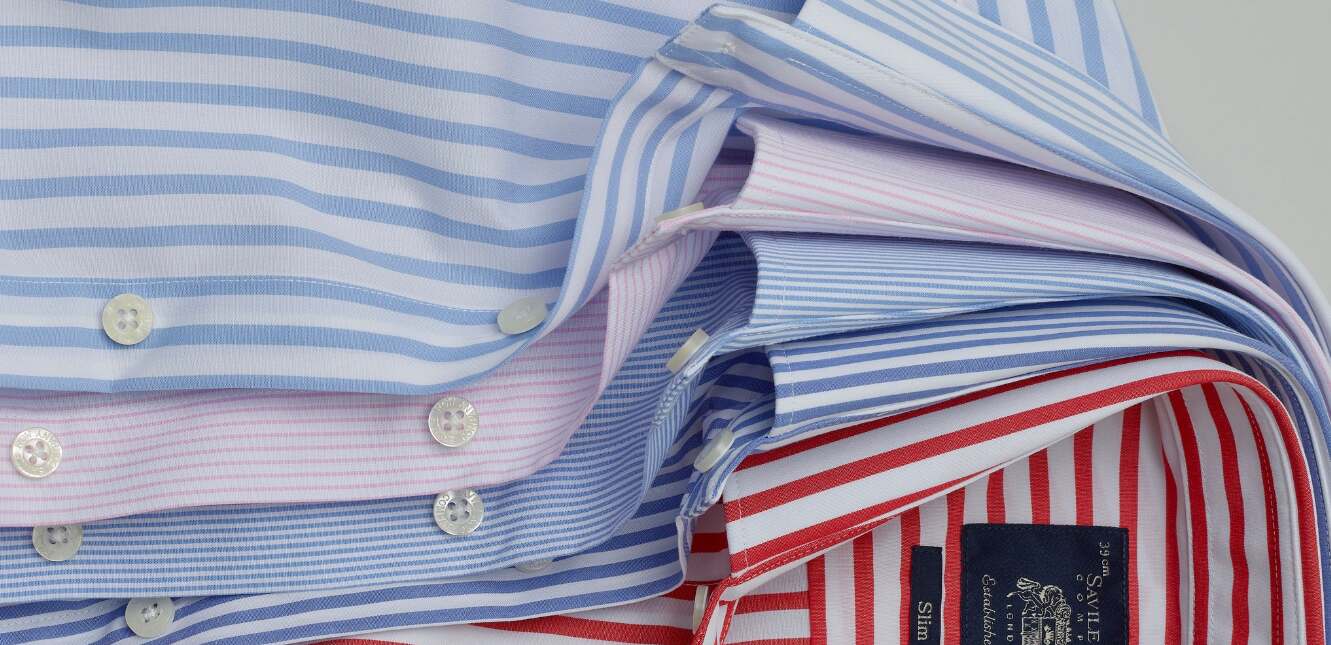 Savile Row Company ways to save money banner - A selection of different colour shirts piled on top of each other