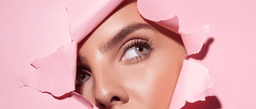 Sculpted By Aimee beauty image featuring a womans face bursting through some pink paper