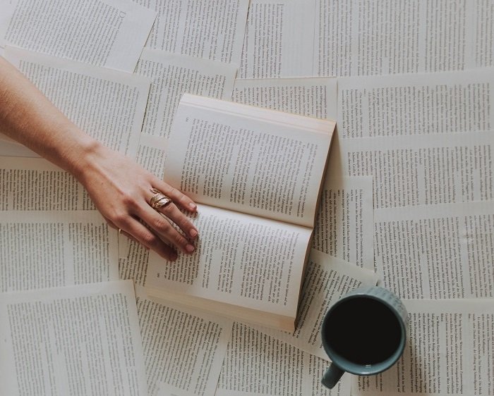 Tasse und Hand über umweltfreundlichen Secondhand Büchern