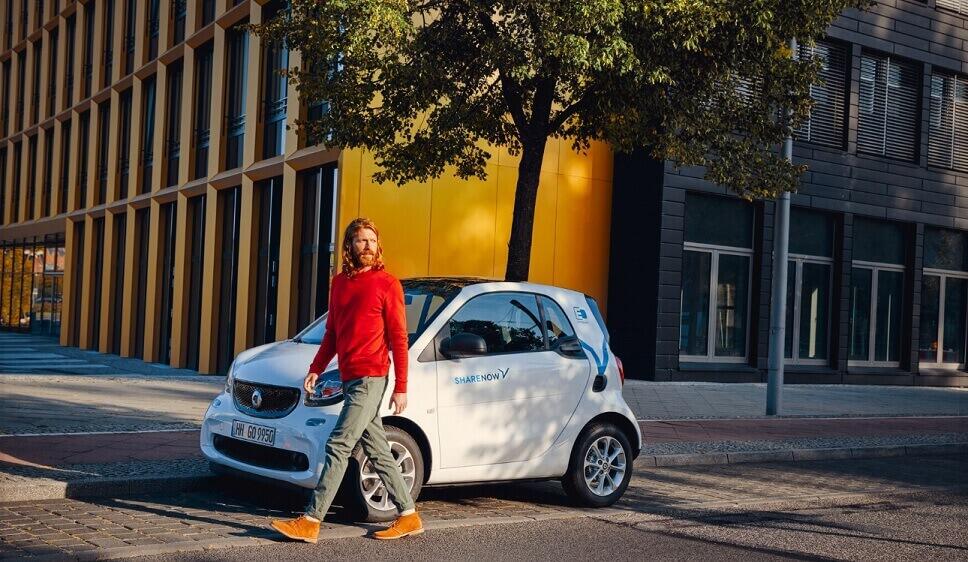 Mann geht von geparktem SHARE NOW Mietauto weg