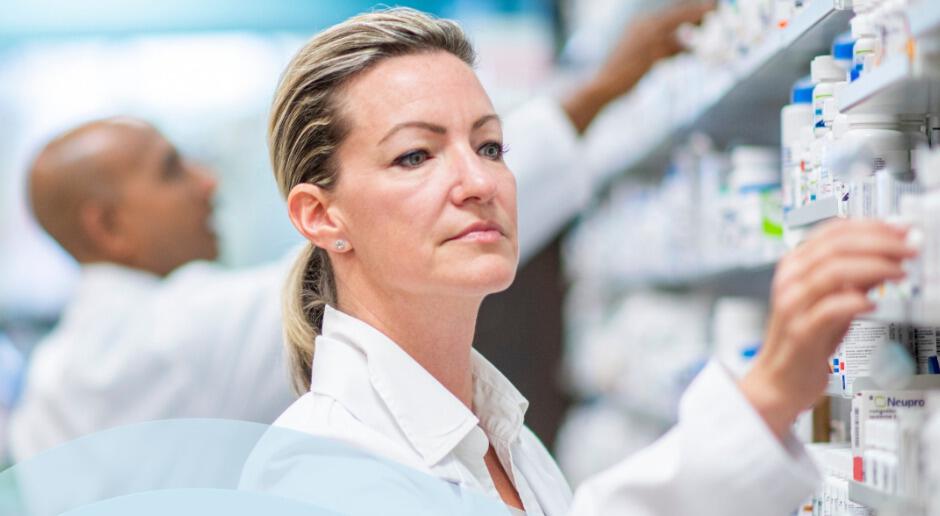 Simply Meds Online savings banner - A femal pharmacist picking a bottle from a shelf of drugs