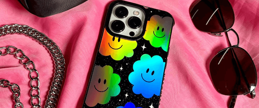Skinnydip London savings guide banner showing a vibrant phone case featuring smiley faces alongside a chain and sunglasses on pink background