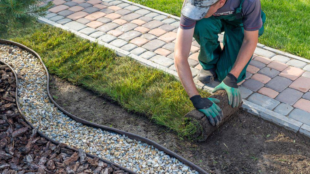 Aerial view of a man laying turf beside a path