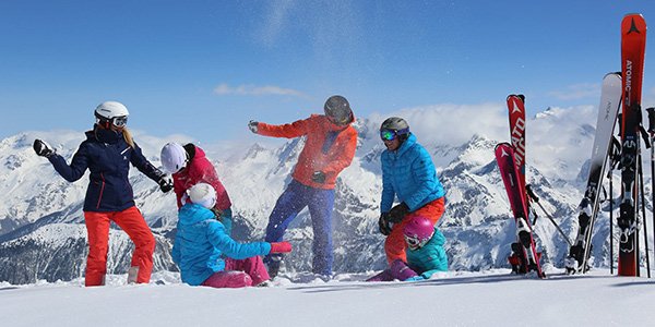 Famille faisant une bataille de boules de neige à côté de skis plantés dans la neige