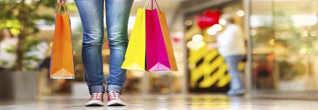 Femme dans un centre commercial avec des sacs de shopping à ses pieds