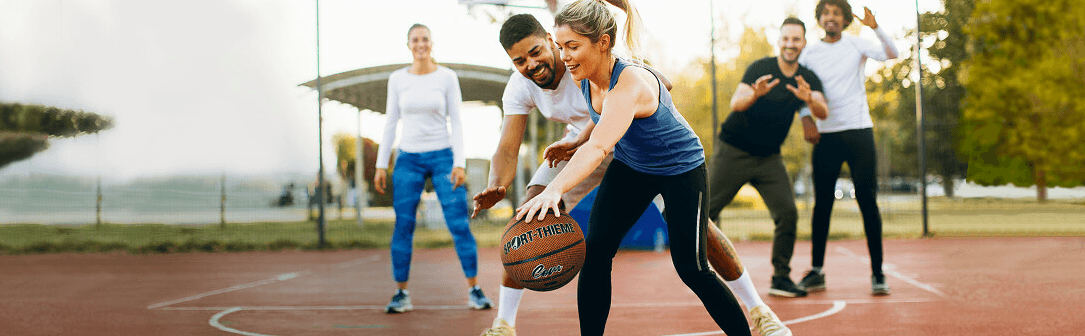 Männer und Frauen spielen Basketball mit einem Sport-Thieme Ball