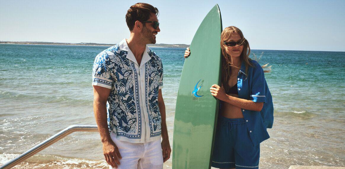 Sportscraft deals page image - A man ond woman on a beach, with the lady holding a surfboard