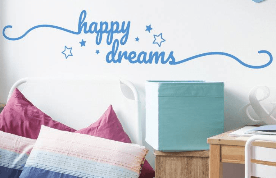 Sticker mural Tenstickers sur lequel on lit Happy Dreams au dessus d&apos;un lit