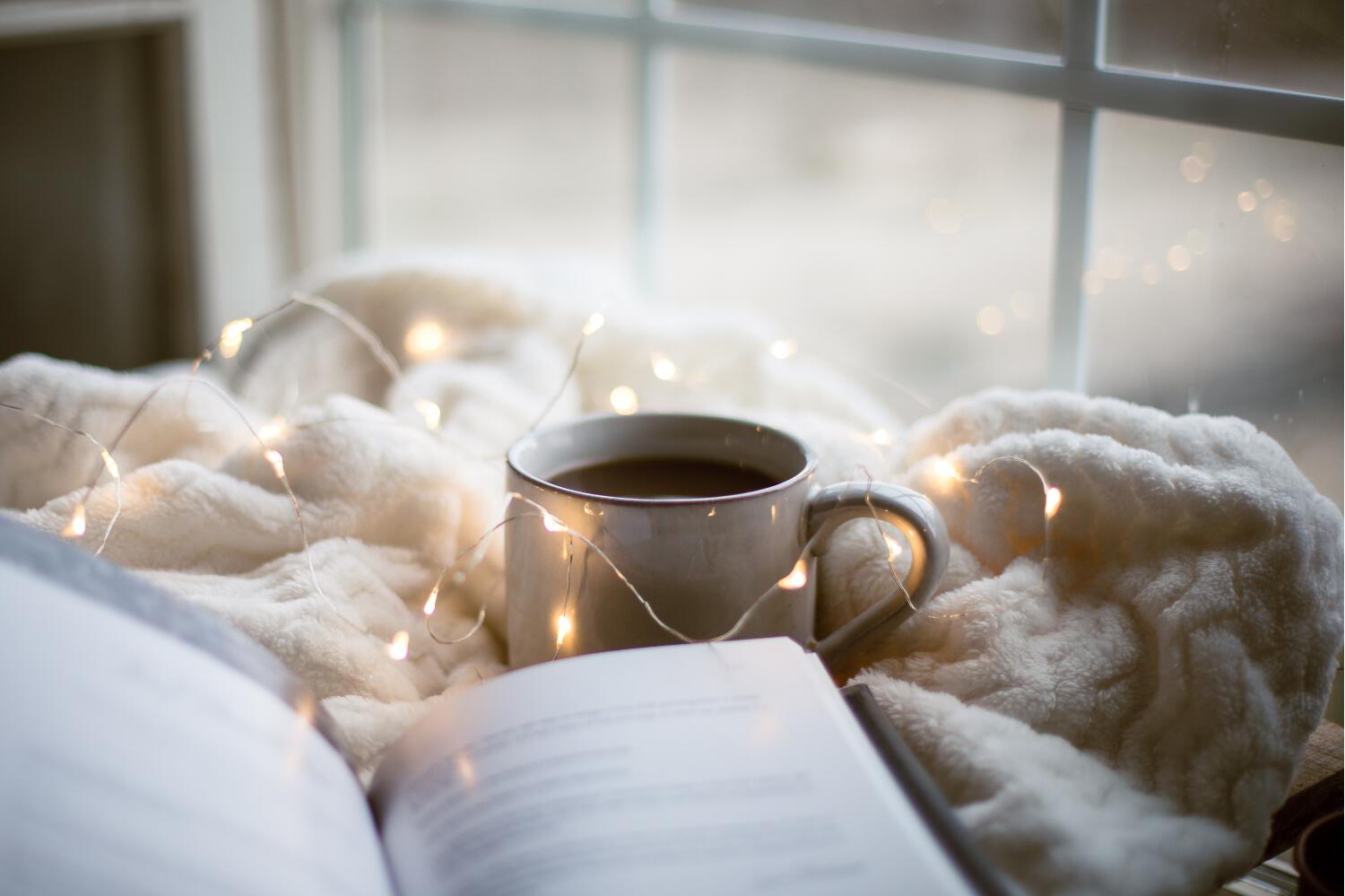 Tasse de café et livre ouvert sur une couverture d'hiver
