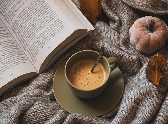 Tasse de café et livre ouvert sur une couverture en automne