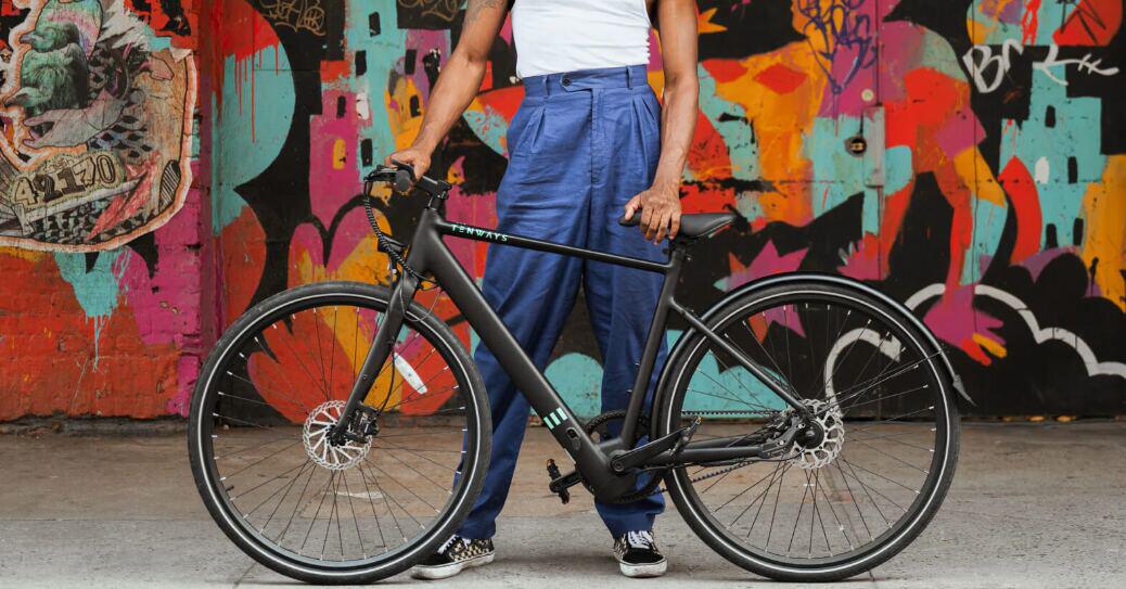 Tenways discounts page - A male supporting a black branded bike in front of vibrant graffiti