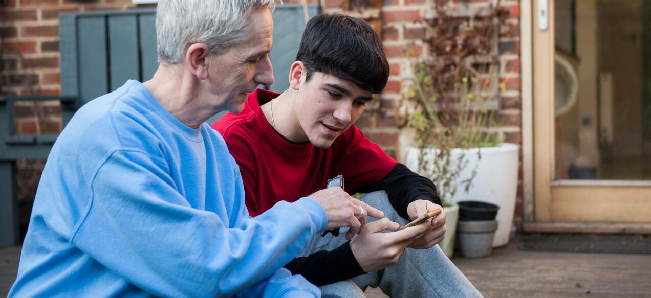 Tesco Mobile deals banner featuring a father and son comparing mobile phones