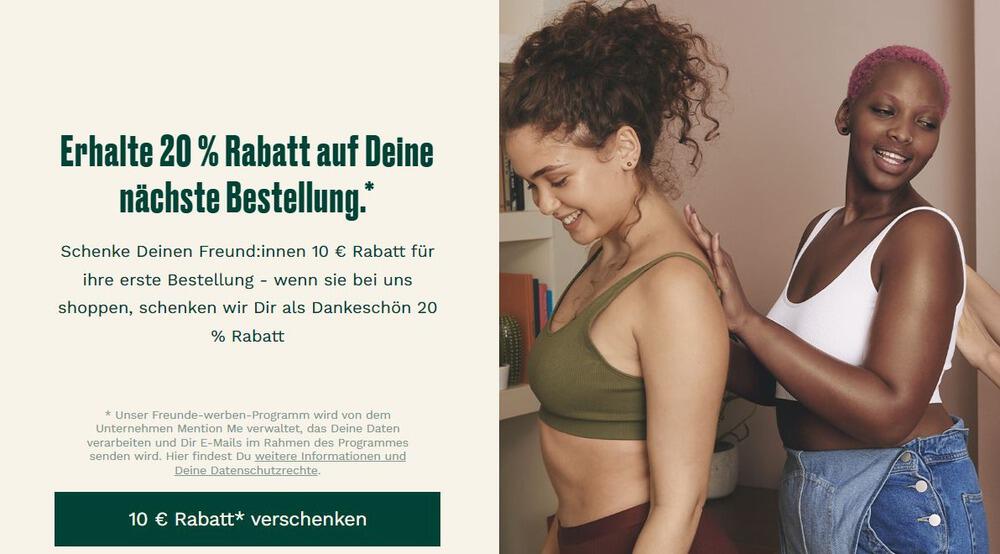 Frau cremt anderer Frau den Rücken ein; Hinweis auf 20 % The Body Shop Gutschein für das Freunde-Werben