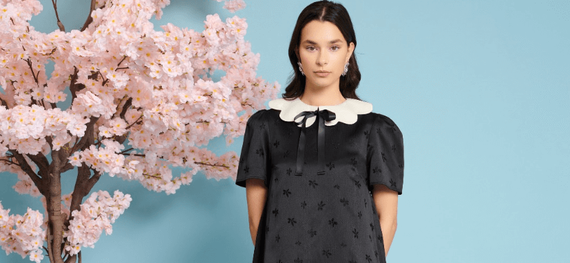 The Hut deals page image - A woman in a black and white dress standing next to a blossom tree